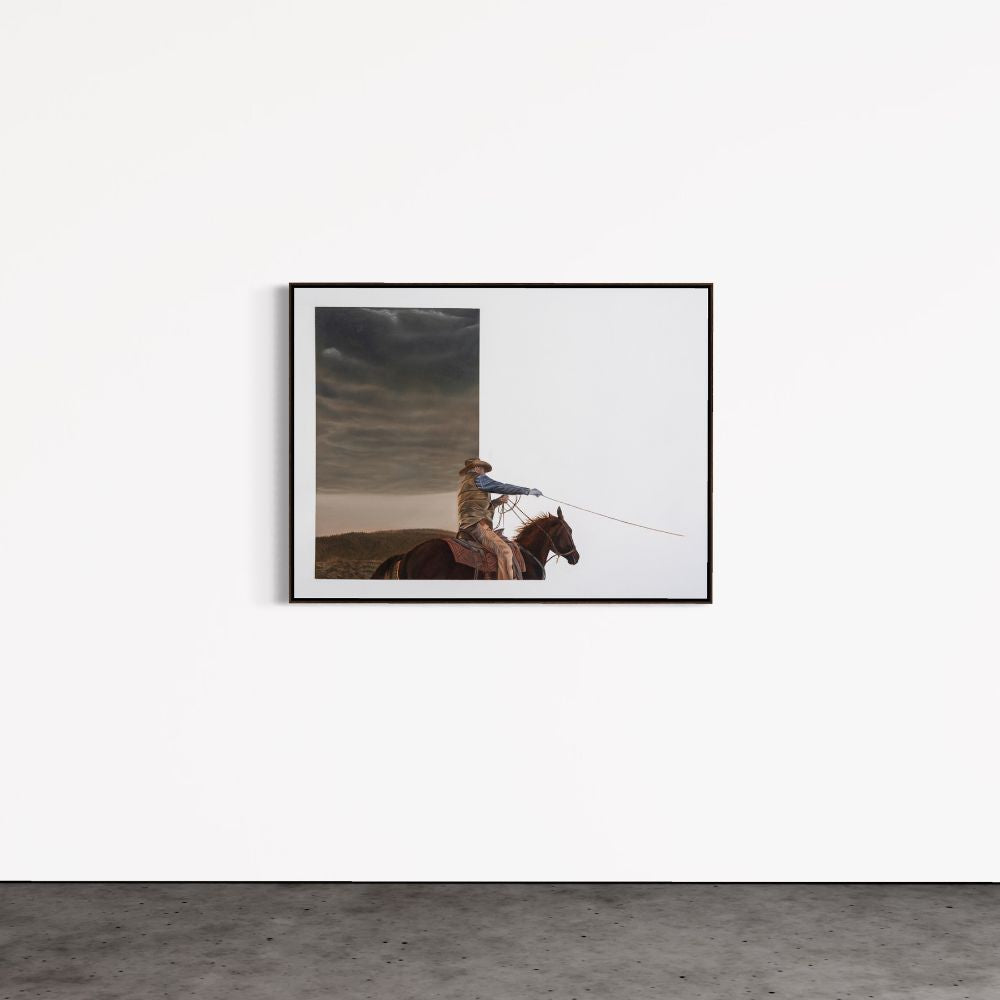 Framed artwork of a person on horseback against a stormy sky, displayed on a white wall.