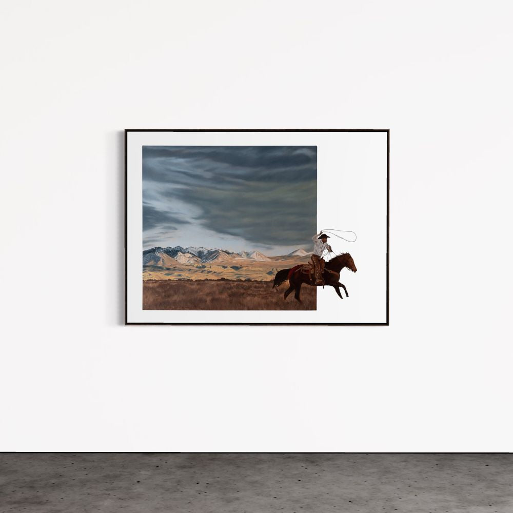 Framed artwork of a cowboy on horseback with mountains in the background