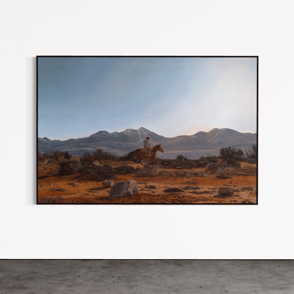 Framed artwork of a desert landscape with mountains and a person on horseback.