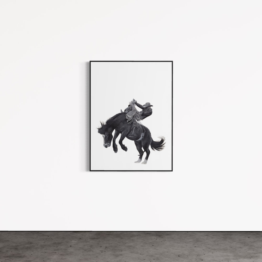 Framed black and white artwork of a horse and rider on a white wall.
