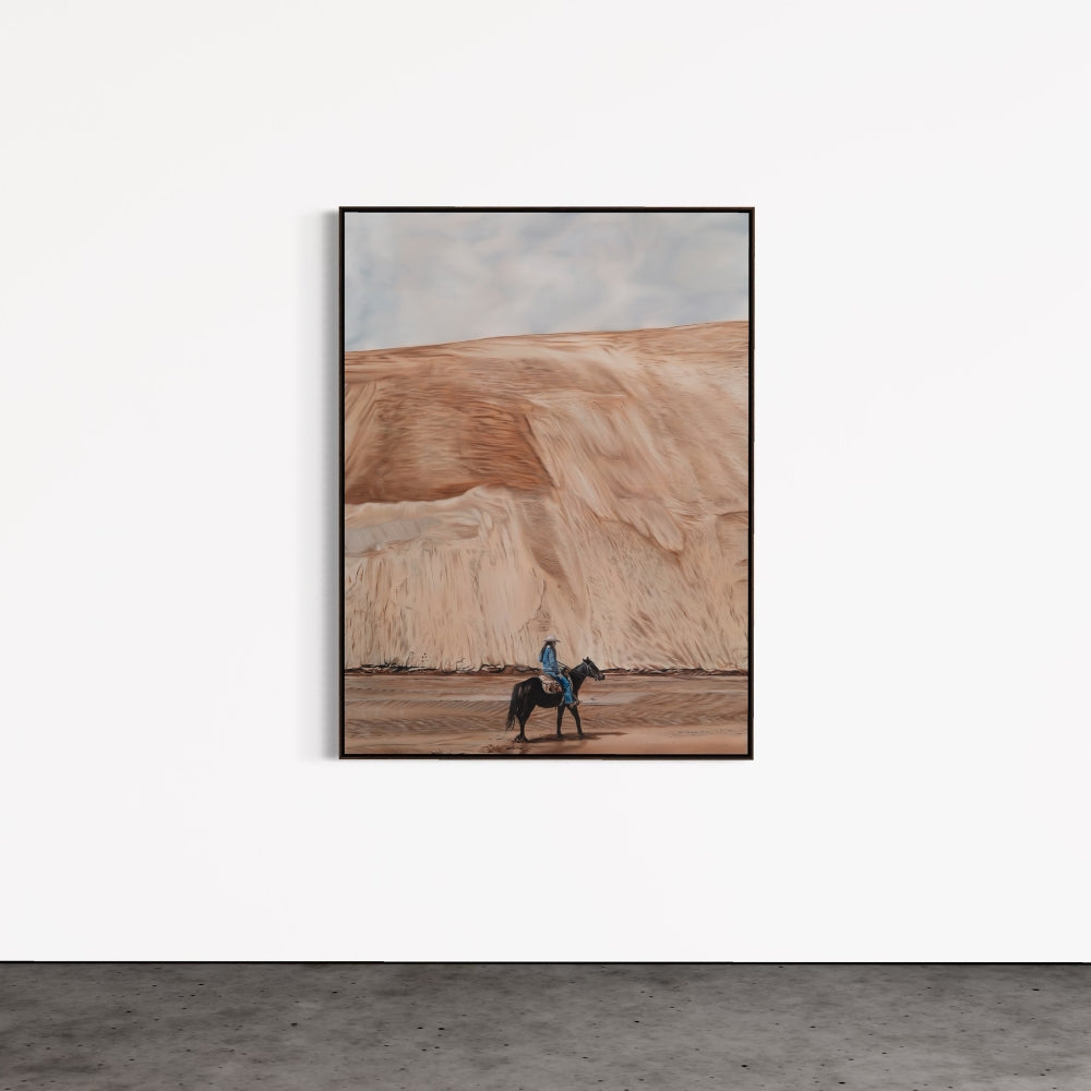 Framed artwork of a person on horseback in a desert landscape on a white wall.