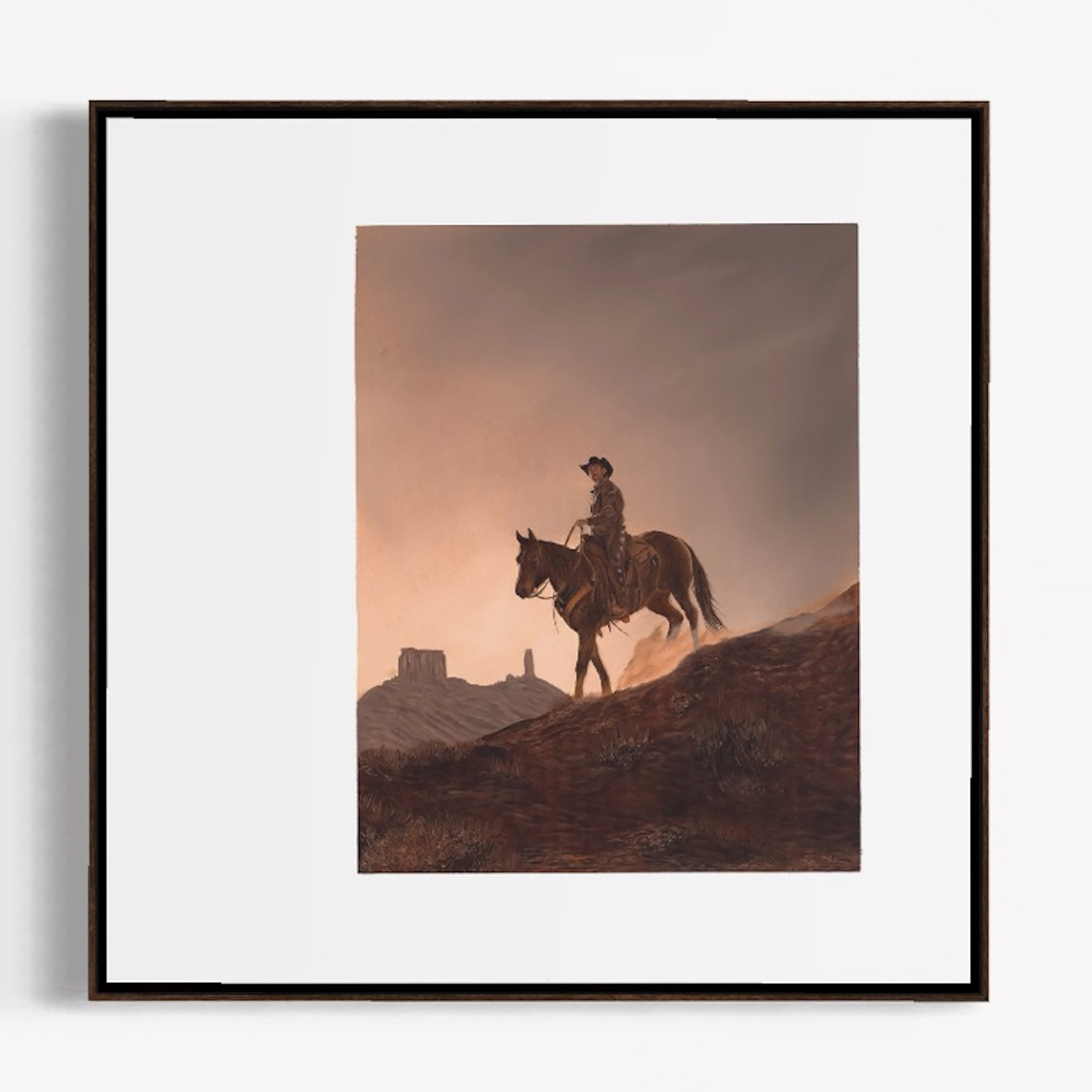 Framed artwork of a cowboy on horseback against a sunset sky.
