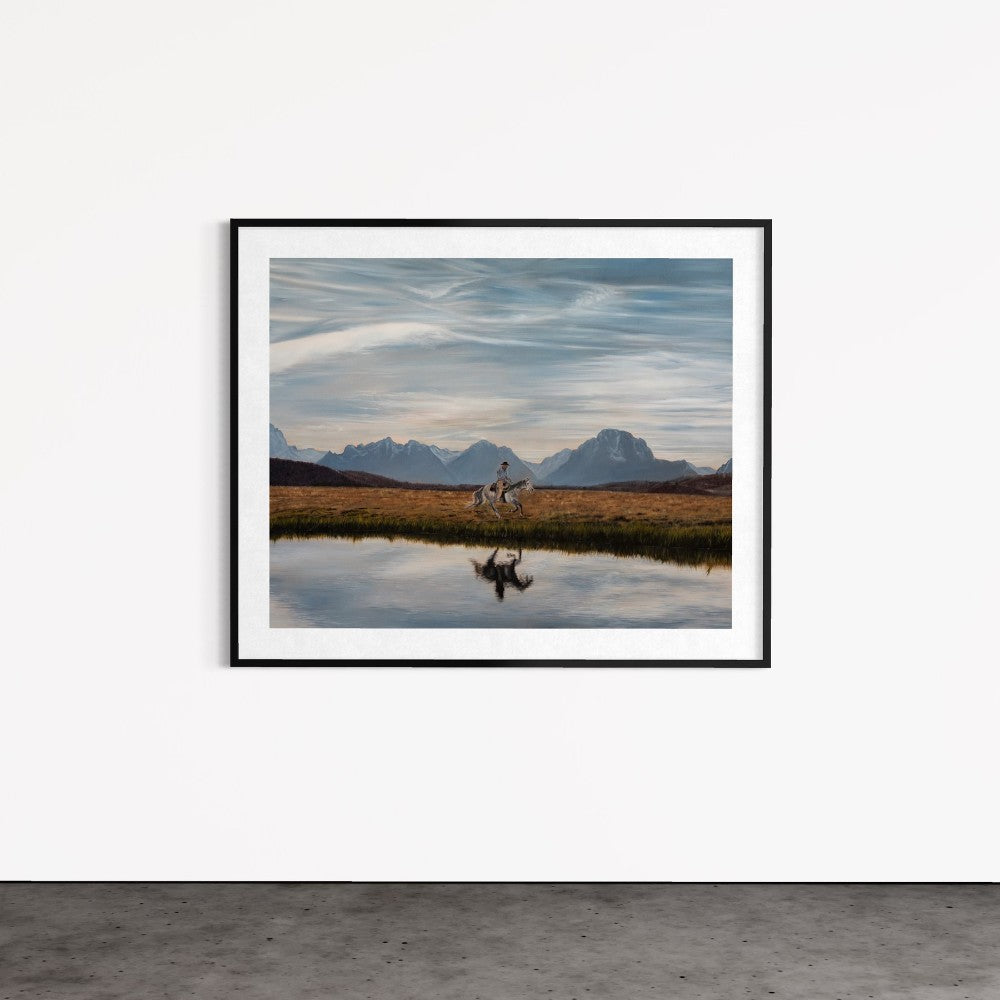 Framed photograph of a landscape with mountains and a person walking near a body of water.