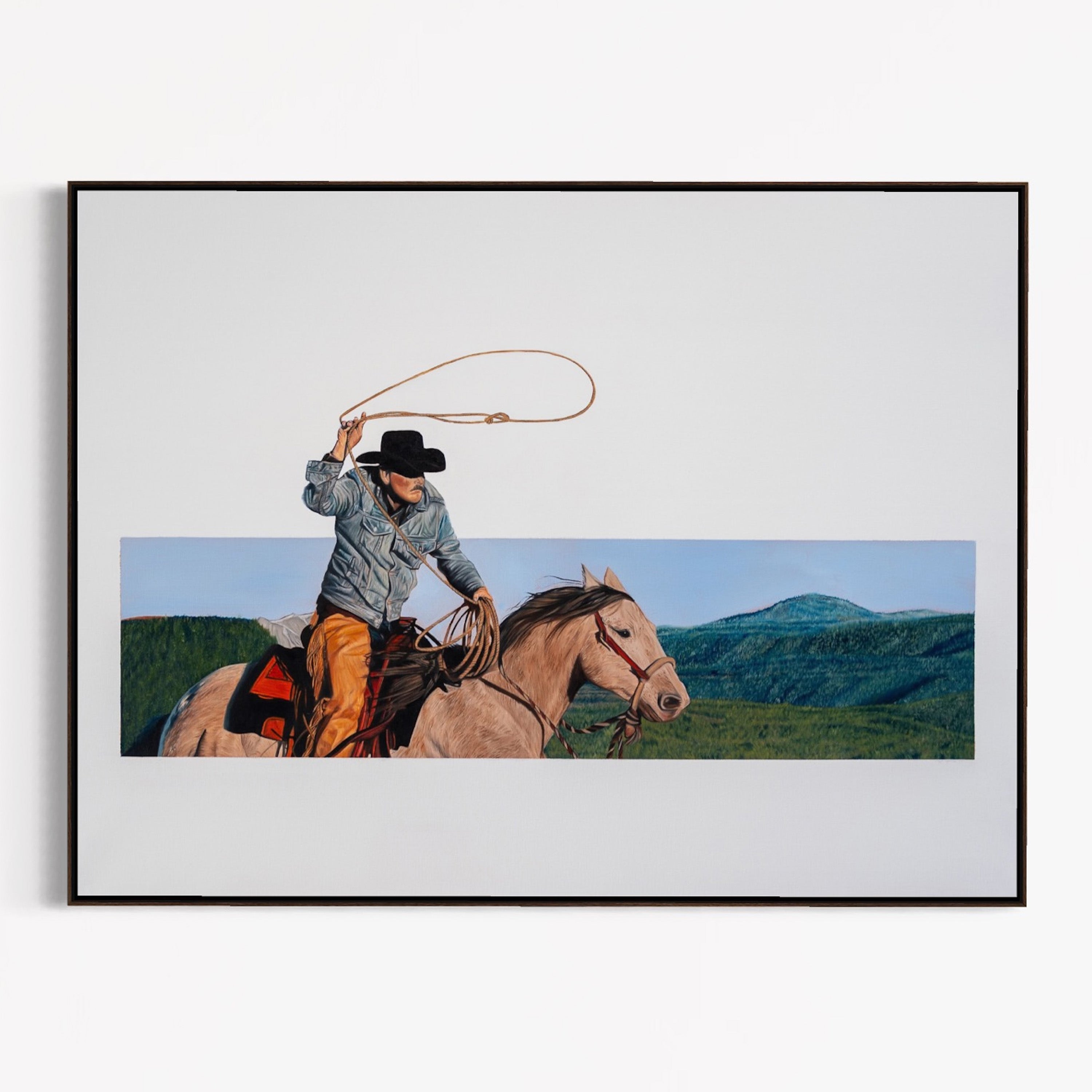 Framed artwork of a cowboy on horseback with mountains in the background
