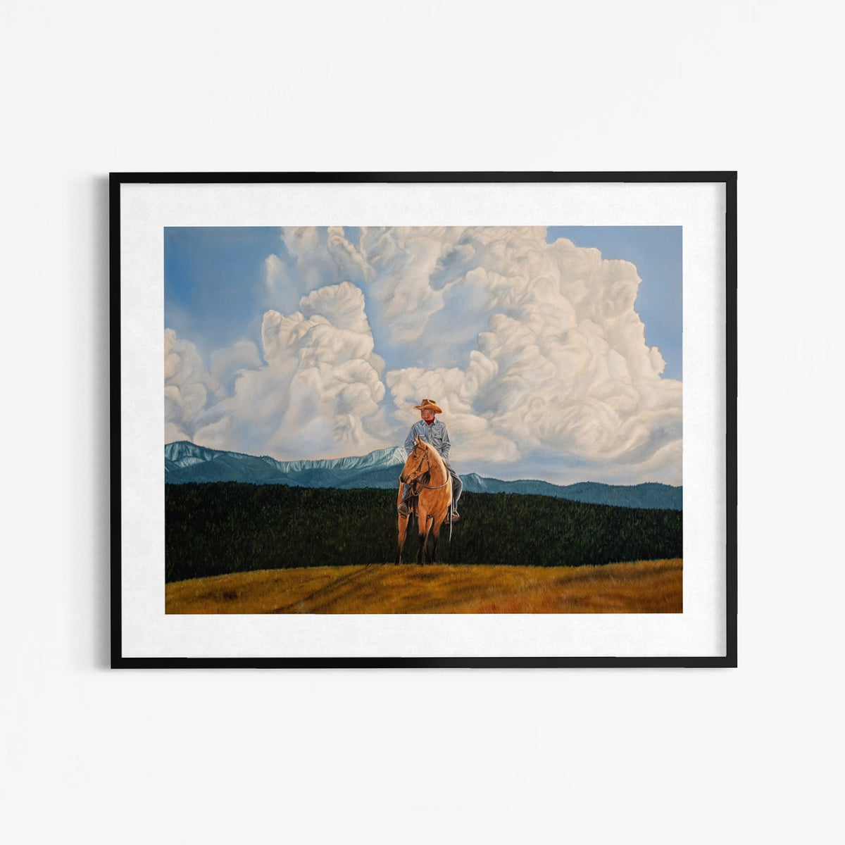 Framed artwork of a person on horseback with mountains and clouds in the background