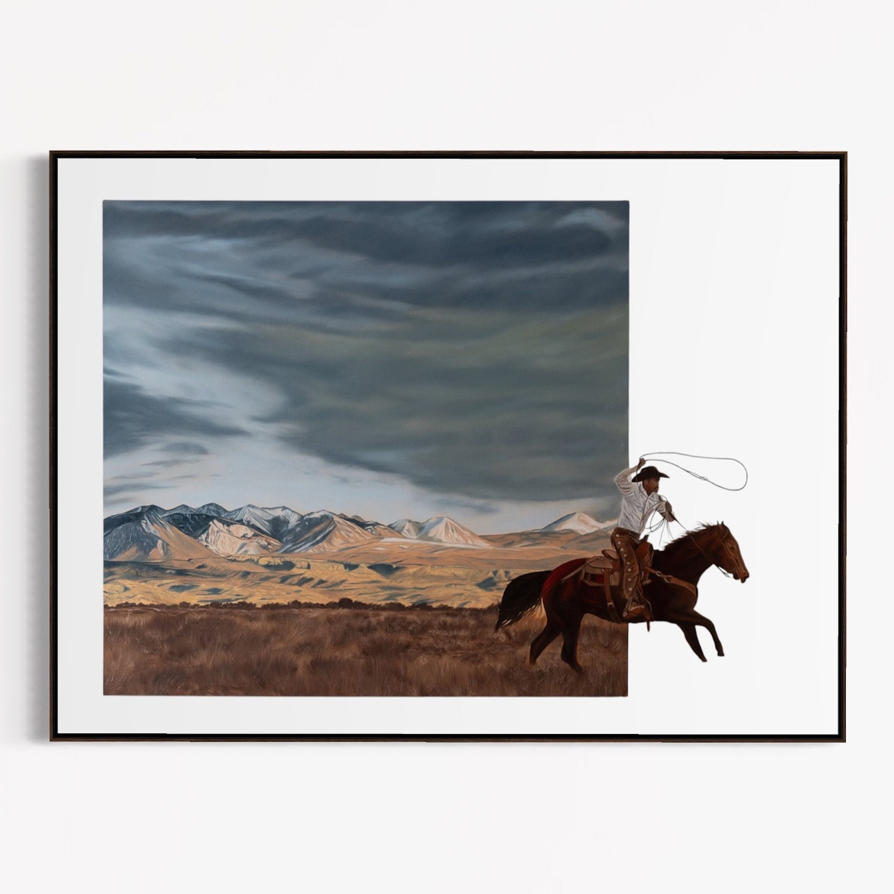 Framed artwork of a cowboy on horseback with mountains in the background