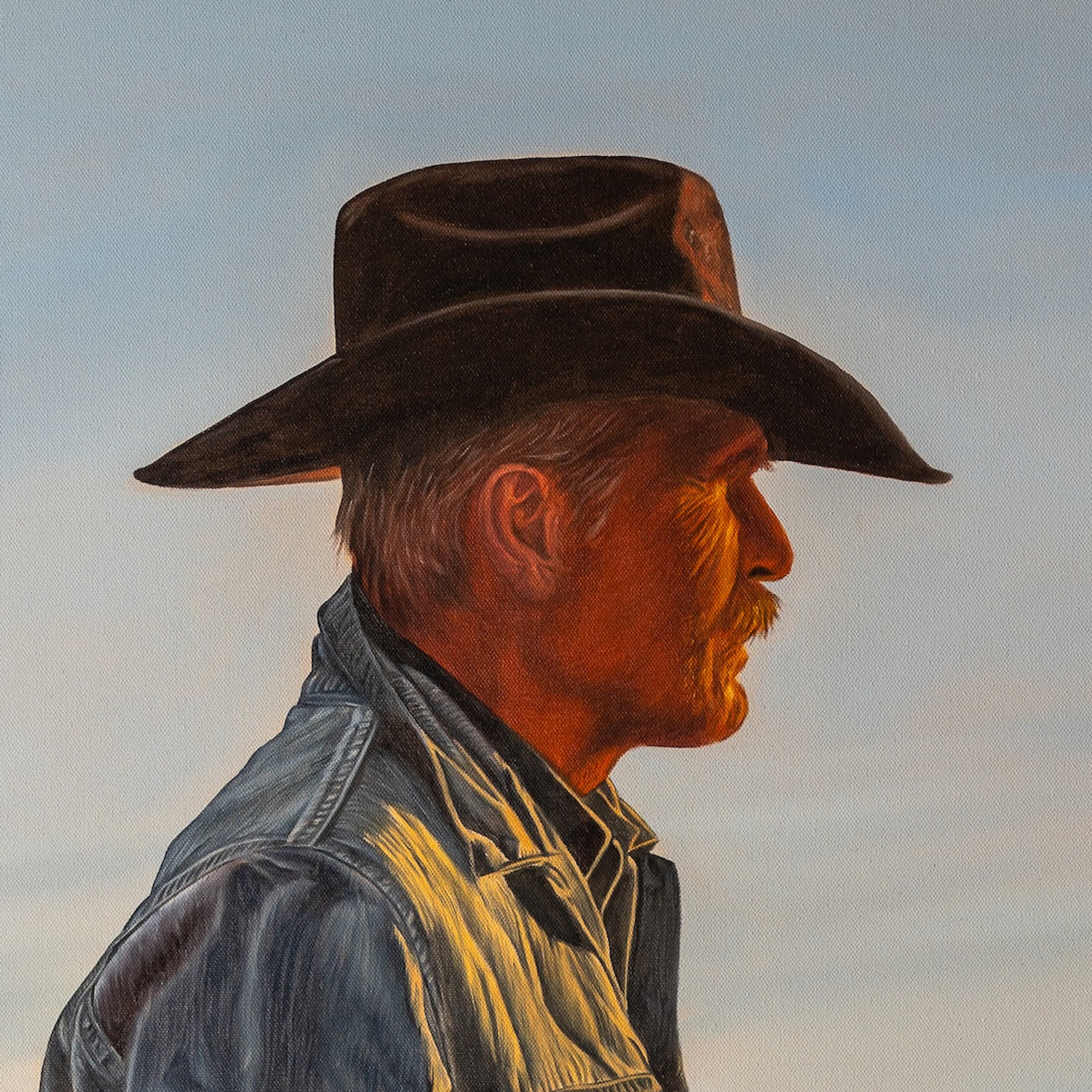 Man wearing a cowboy hat and denim jacket against a sky background