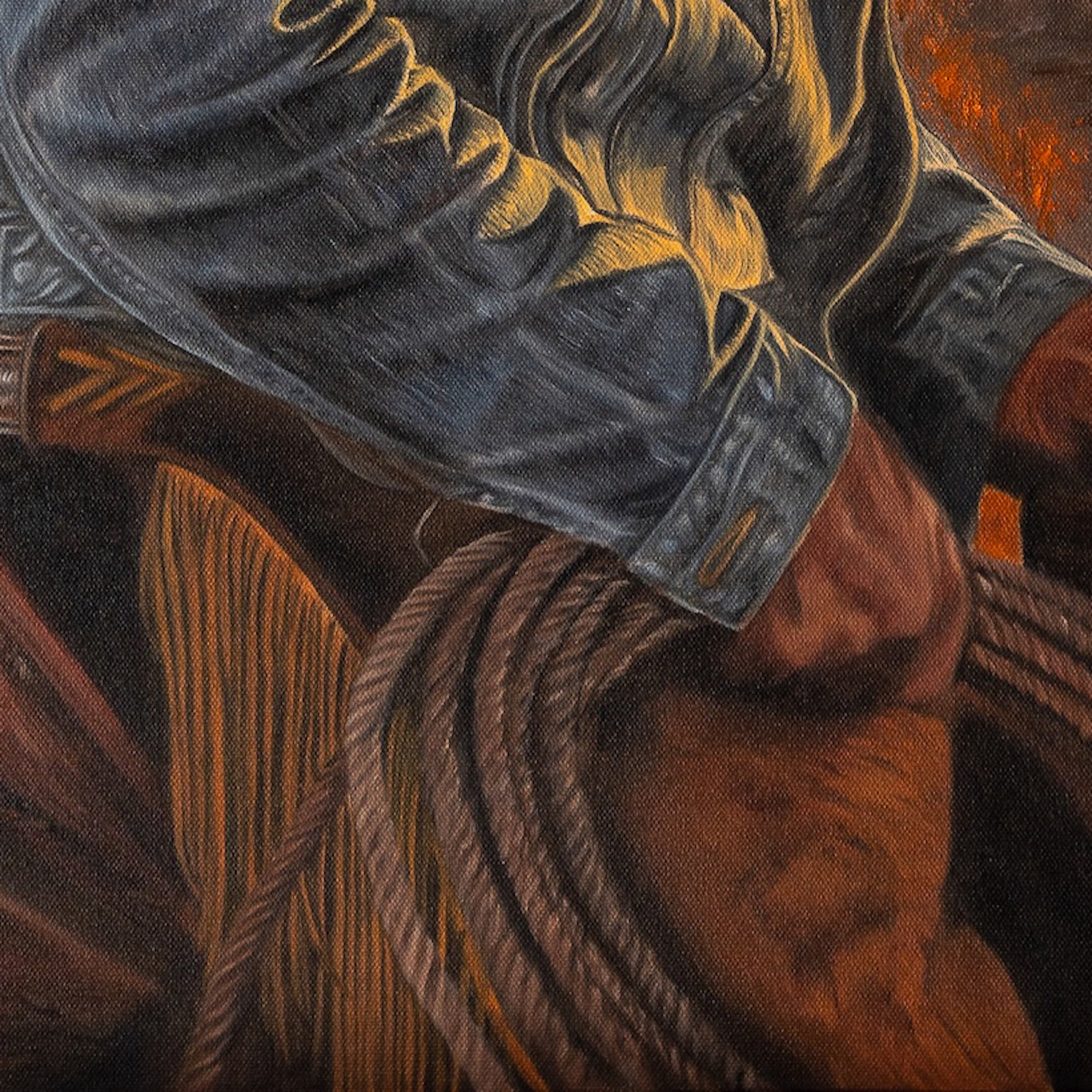Close-up of a cowboy boot and chaps with a horse in the background