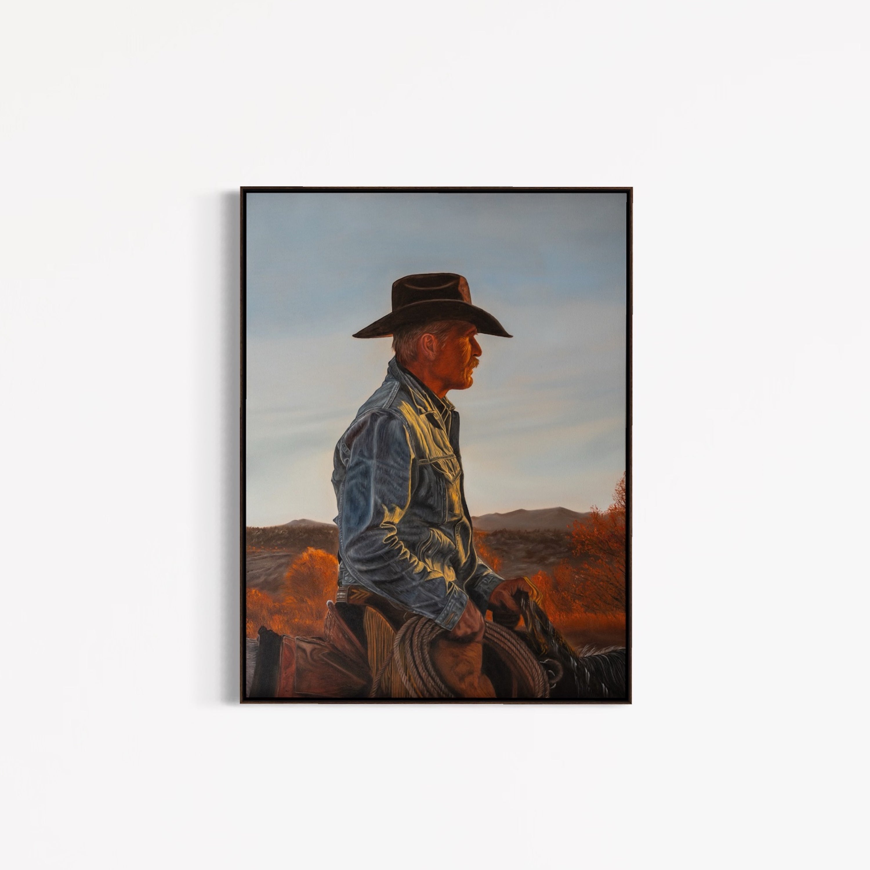 Framed artwork of a cowboy sitting on a horse with a desert landscape in the background.