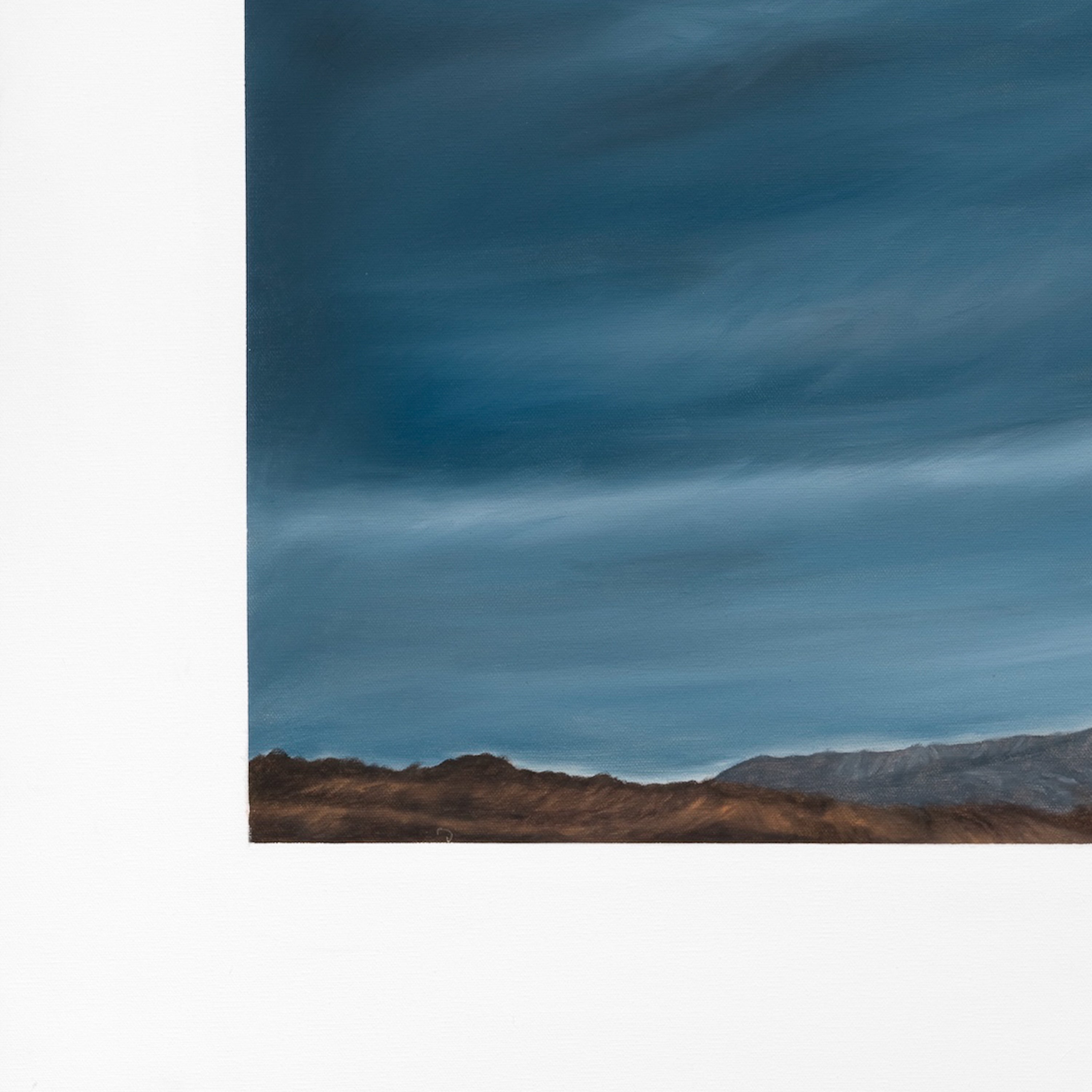 Long exposure of a blue sky with cloud patterns over a desert landscape.