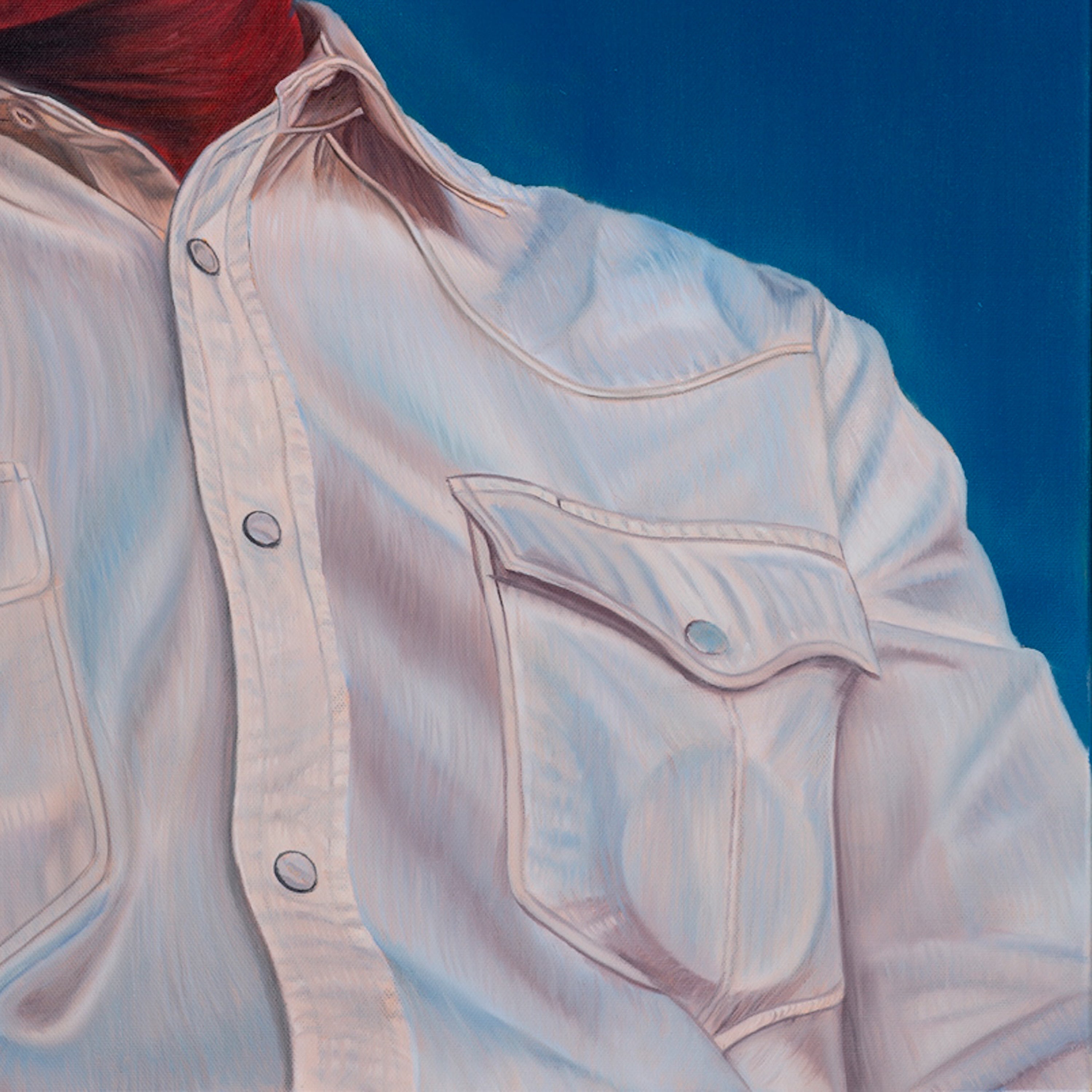 Close-up of a light-colored denim jacket with a red garment underneath on a blue background